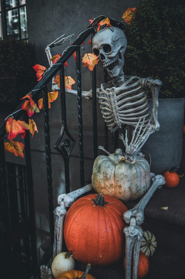 Skeleton decoration on front steps with pumpkins and autumn leaves