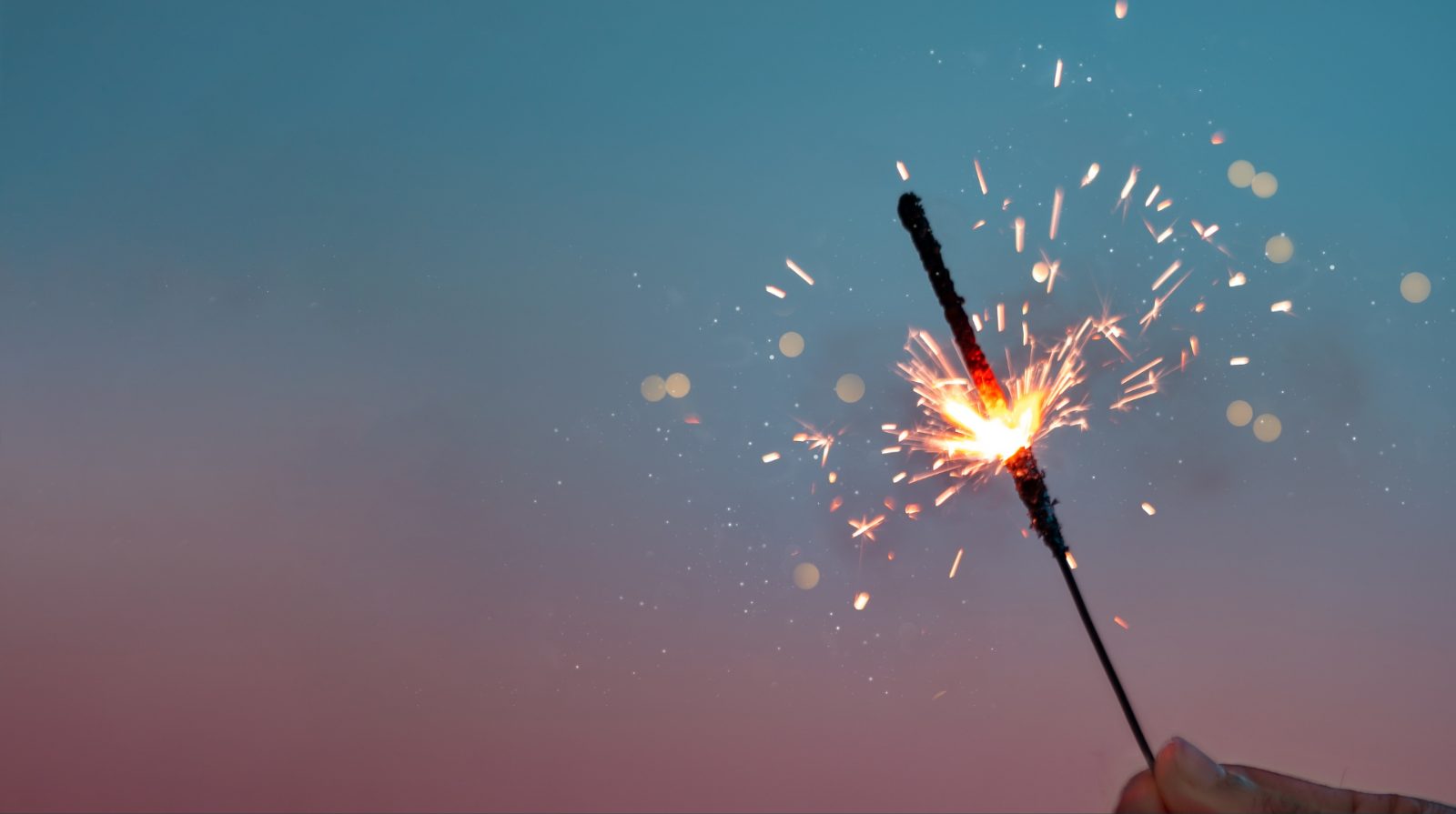 Lit sparkler against a dusk sky